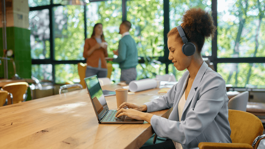 Young woman in headphones using laptop for online work