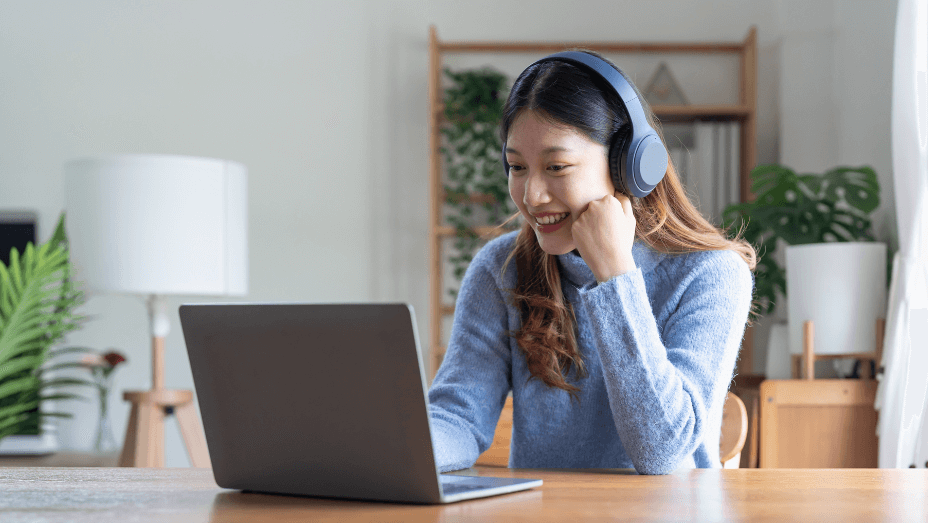 Young asian woman talk on video call at the table using headphones