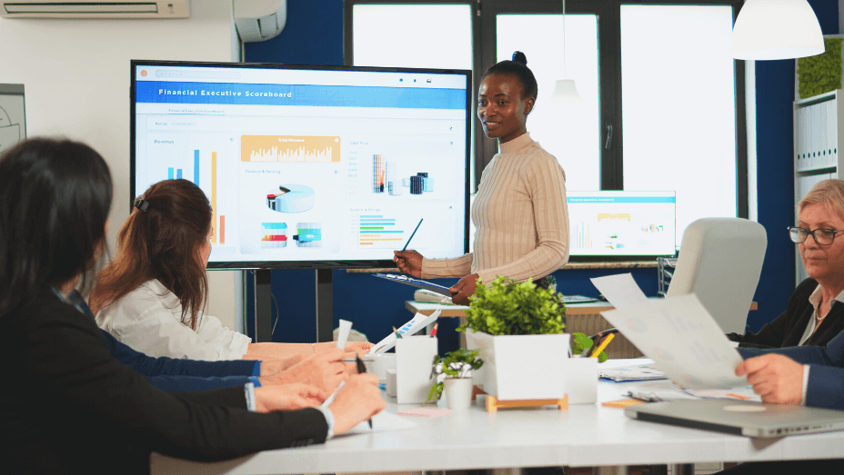 woman worker explaning company statistics in front of colleagues on a digital screen