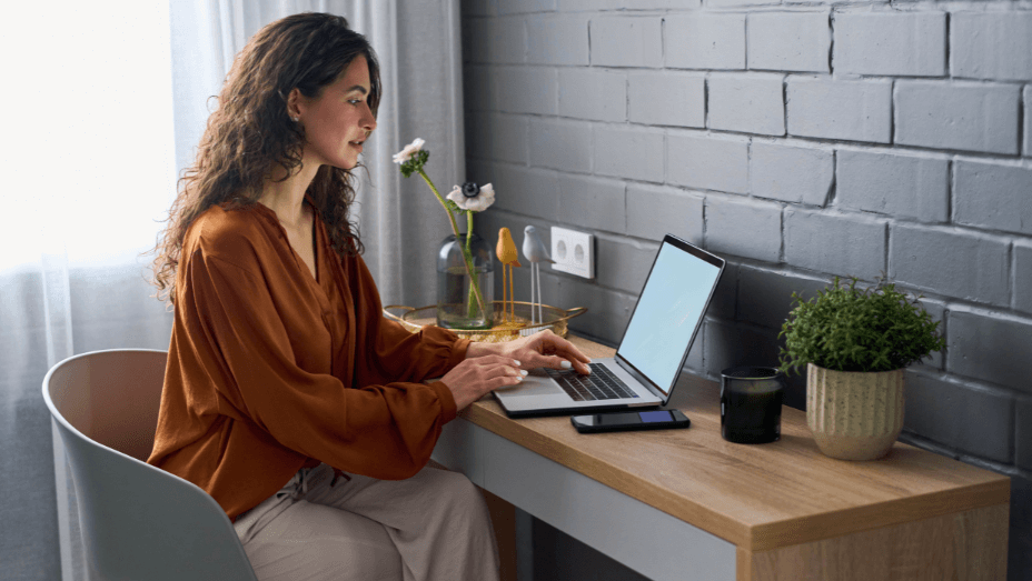 Side view of young female entrepreneur in casualwear sitting by workplace