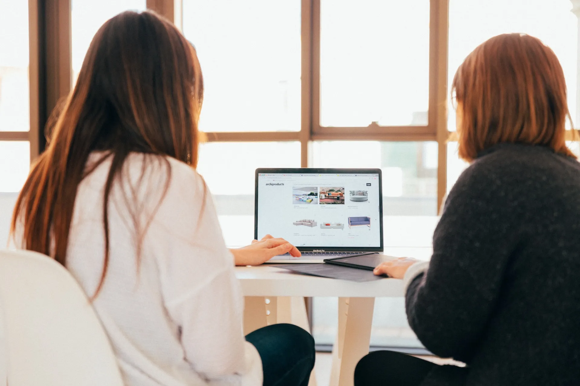 Two women collaborating at a laptop in a modern office environment