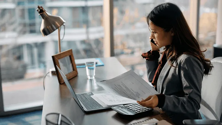 Businesswoman talking on cell phone while working