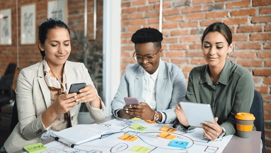 multiracial group of happy businesswomen using workplace technology
