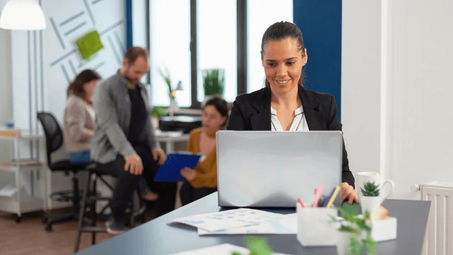 happy hispanic lady typing on laptop sitting at desktop